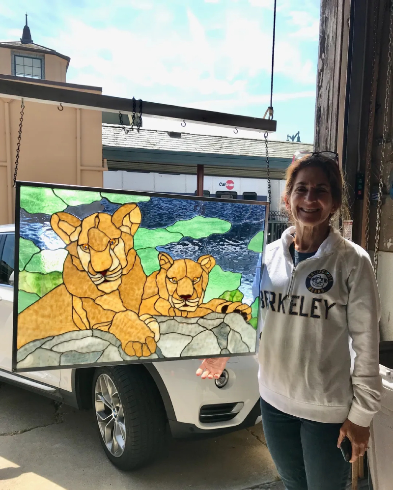 A woman standing next to a painting of two lions.