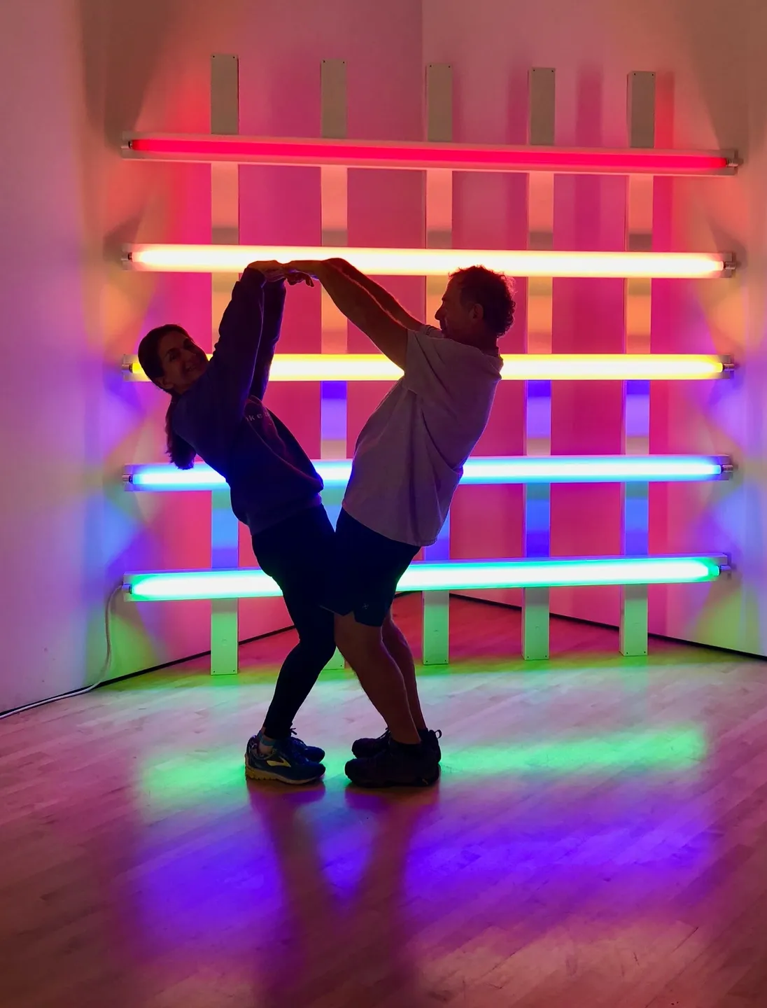 Two people are dancing in a room with neon lights.