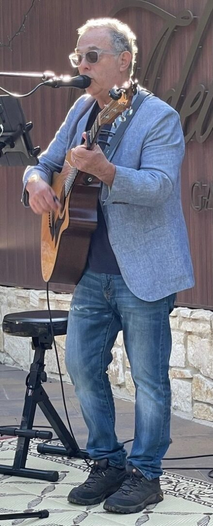 A man in blue jeans and a jacket playing an instrument.